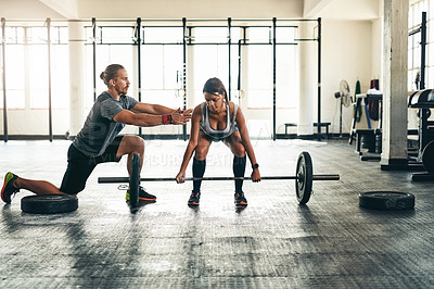 Buy stock photo Shot of a fitness instructor helping a client with weight training at the gym