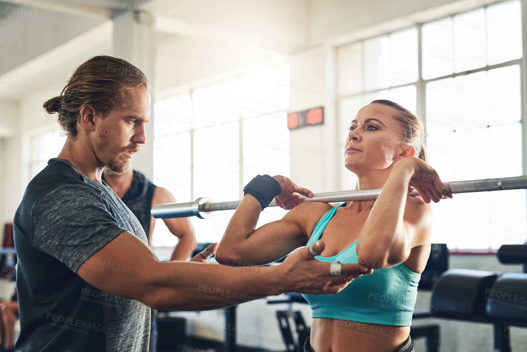Buy stock photo Shot of a fitness instructor helping a client with weight training at the gym