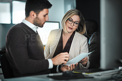 Buy stock photo Shot of two businesspeople discussing a document while sitting at a desk