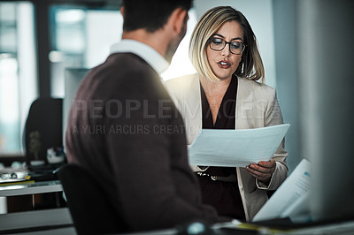 Buy stock photo Shot of two businesspeople discussing a document while sitting at a desk