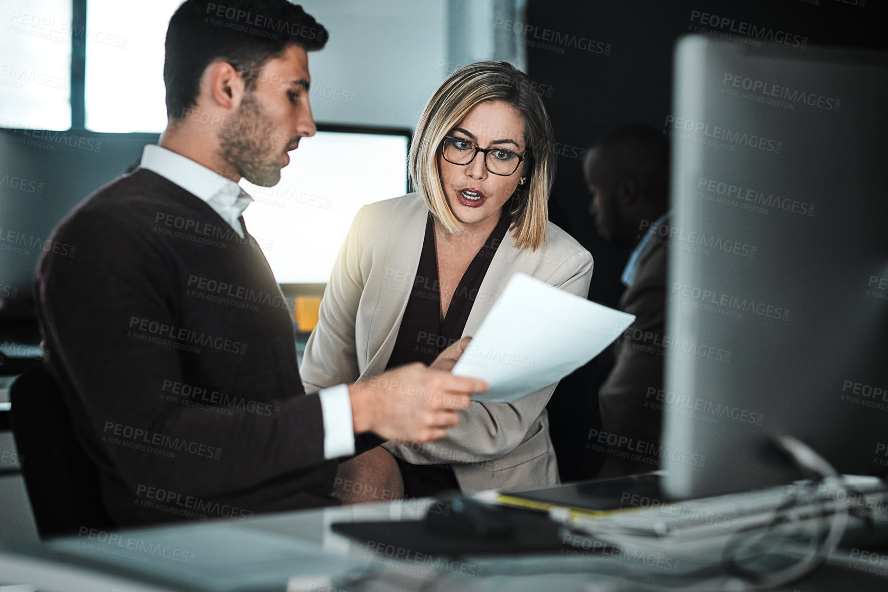 Buy stock photo Shot of two businesspeople discussing a document while sitting at a desk