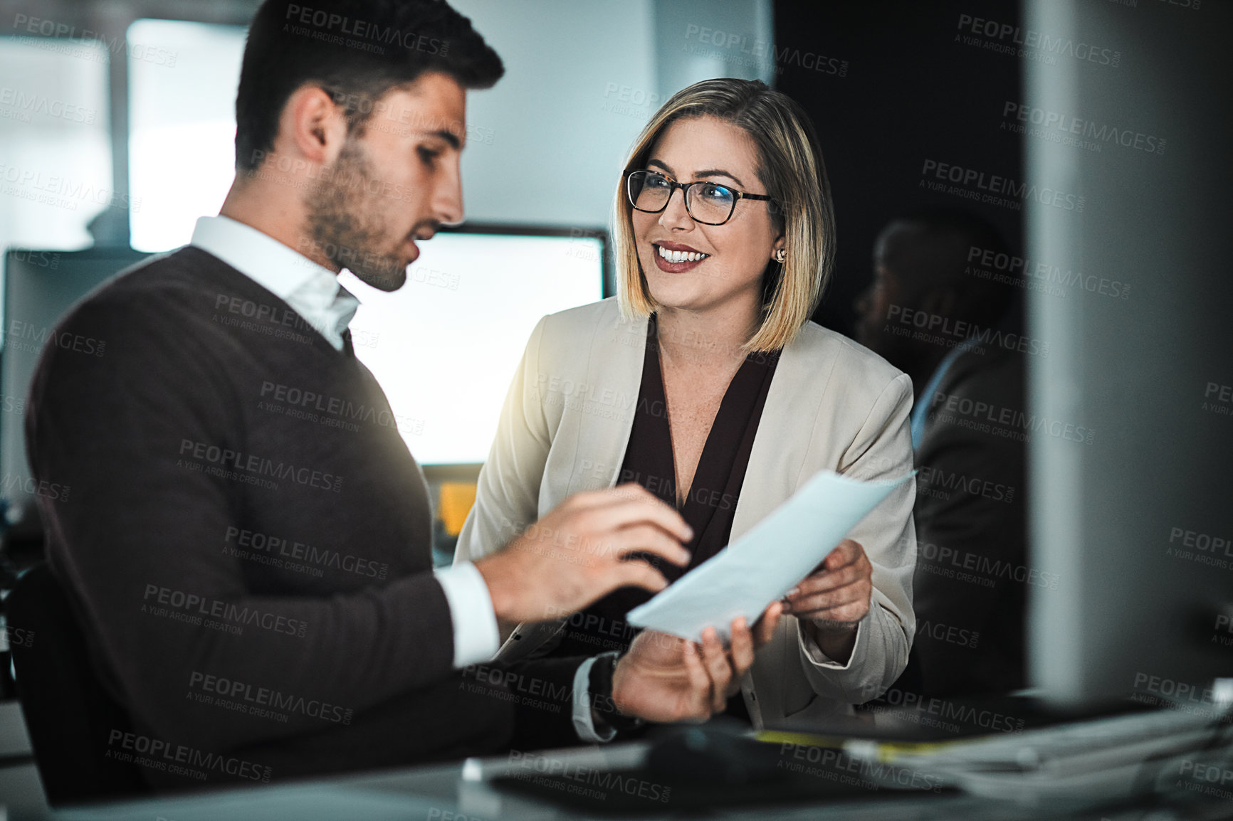 Buy stock photo Shot of two businesspeople discussing a document while sitting at a desk