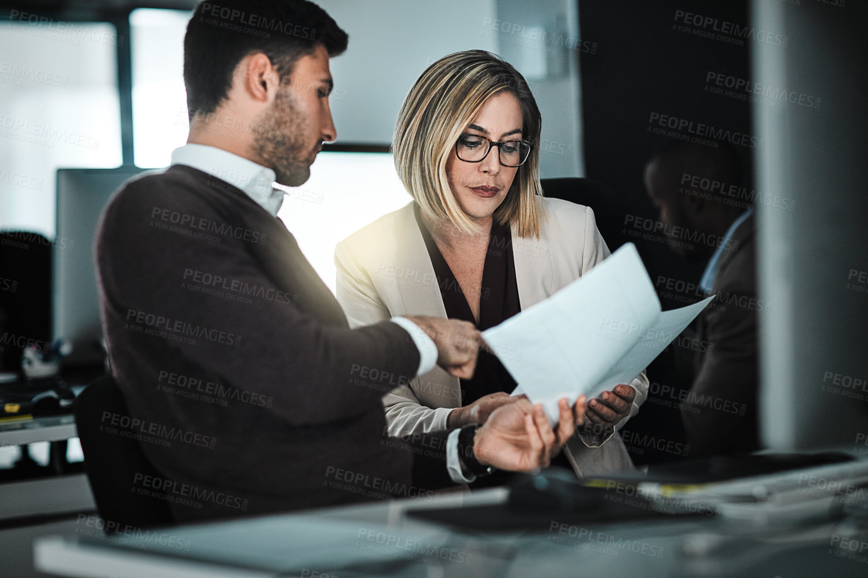 Buy stock photo Shot of two businesspeople discussing paperwork