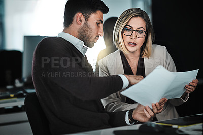Buy stock photo Shot of two businesspeople discussing paperwork
