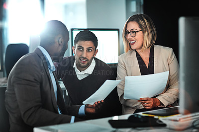 Buy stock photo Shot of three businesspeople discussing paperwork