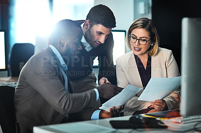 Buy stock photo Shot of three businesspeople discussing paperwork
