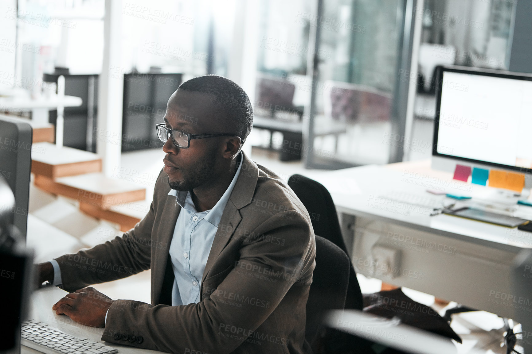 Buy stock photo Cropped shot of a young businessman working on his computer at his desk