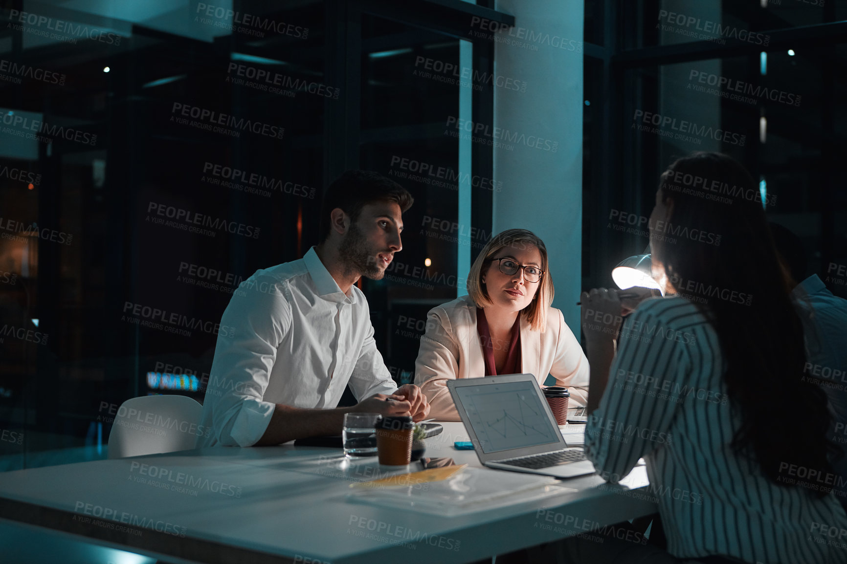 Buy stock photo Shot of colleagues having a meeting during a late night in a modern office