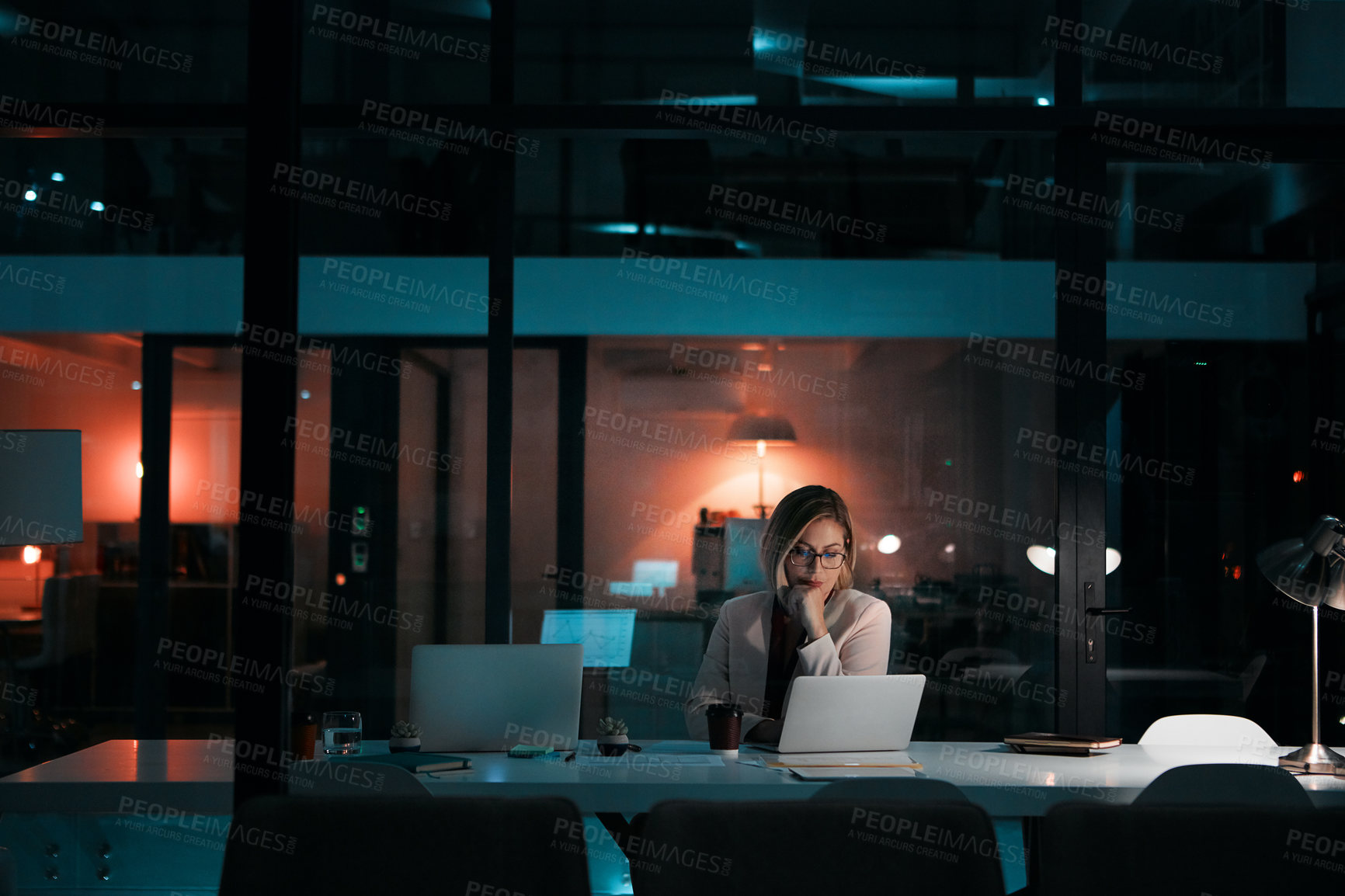 Buy stock photo Shot of a businesswoman using a laptop at her desk during a late night at work