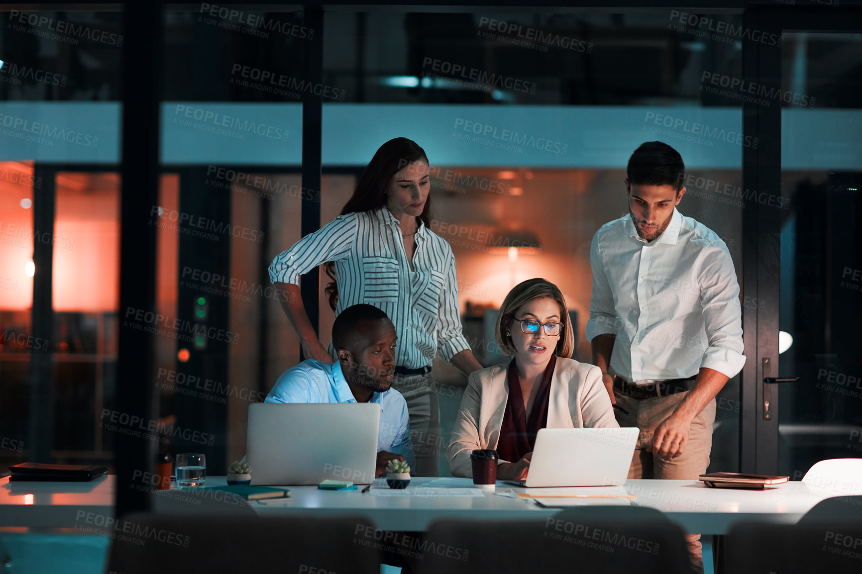 Buy stock photo Shot of colleagues using a laptop together during a late night in a modern office
