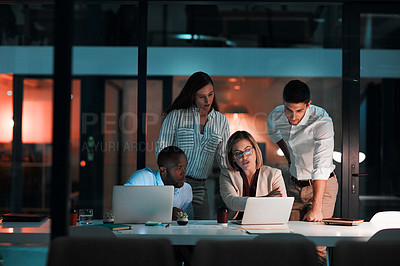 Buy stock photo Shot of colleagues using a laptop together during a late night in a modern office