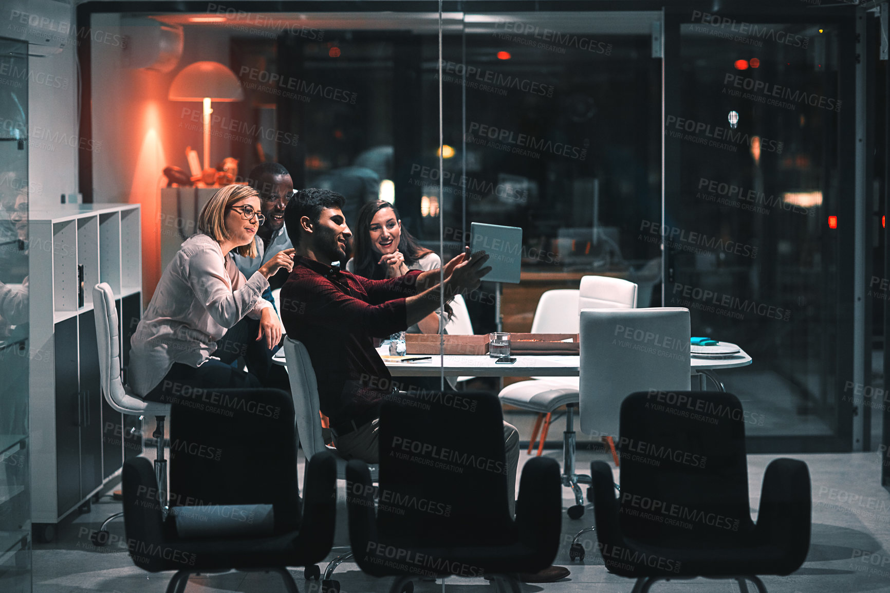 Buy stock photo Shot of colleagues using a digital tablet together during a late night meeting at work