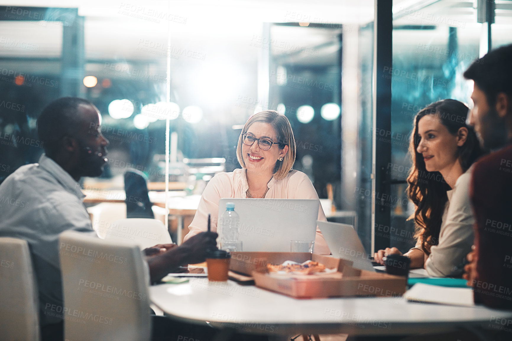 Buy stock photo Teamwork, late night and business people at workshop table with ideas, laptop and pizza at creative agency. Proposal, overtime and diversity, dinner for men and women brainstorming at startup project