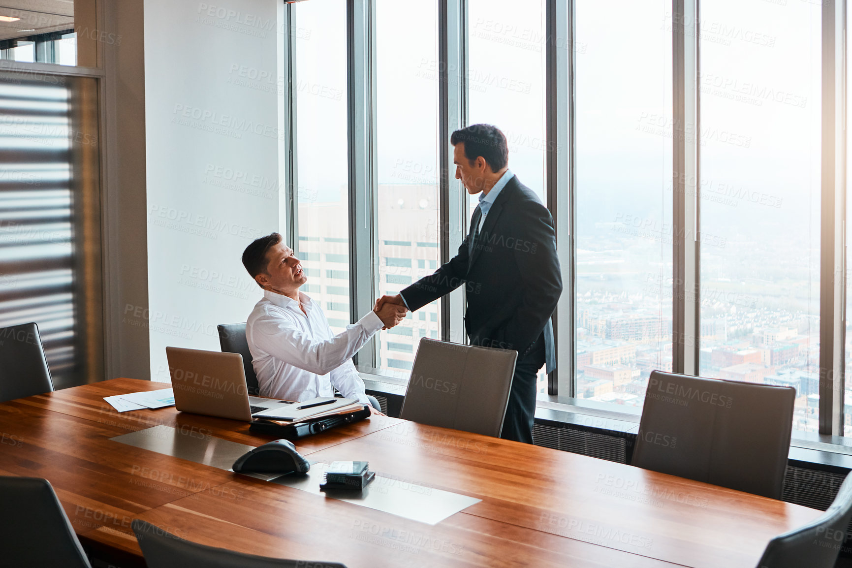 Buy stock photo Shot of two businessmen shaking hands in a corporate office