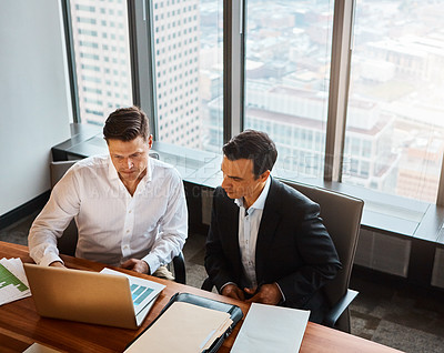 Buy stock photo Shot of two businessmen having a discussion while sitting by a laptop