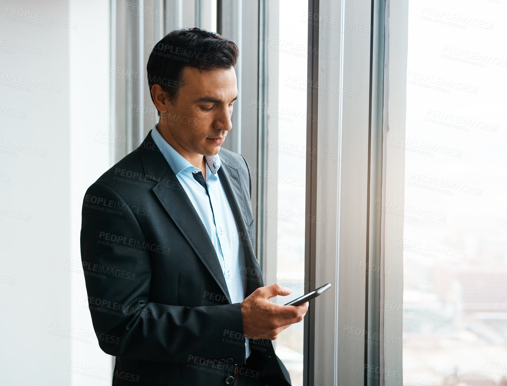 Buy stock photo Shot of a well-dressed businessman using his cellphone at the office