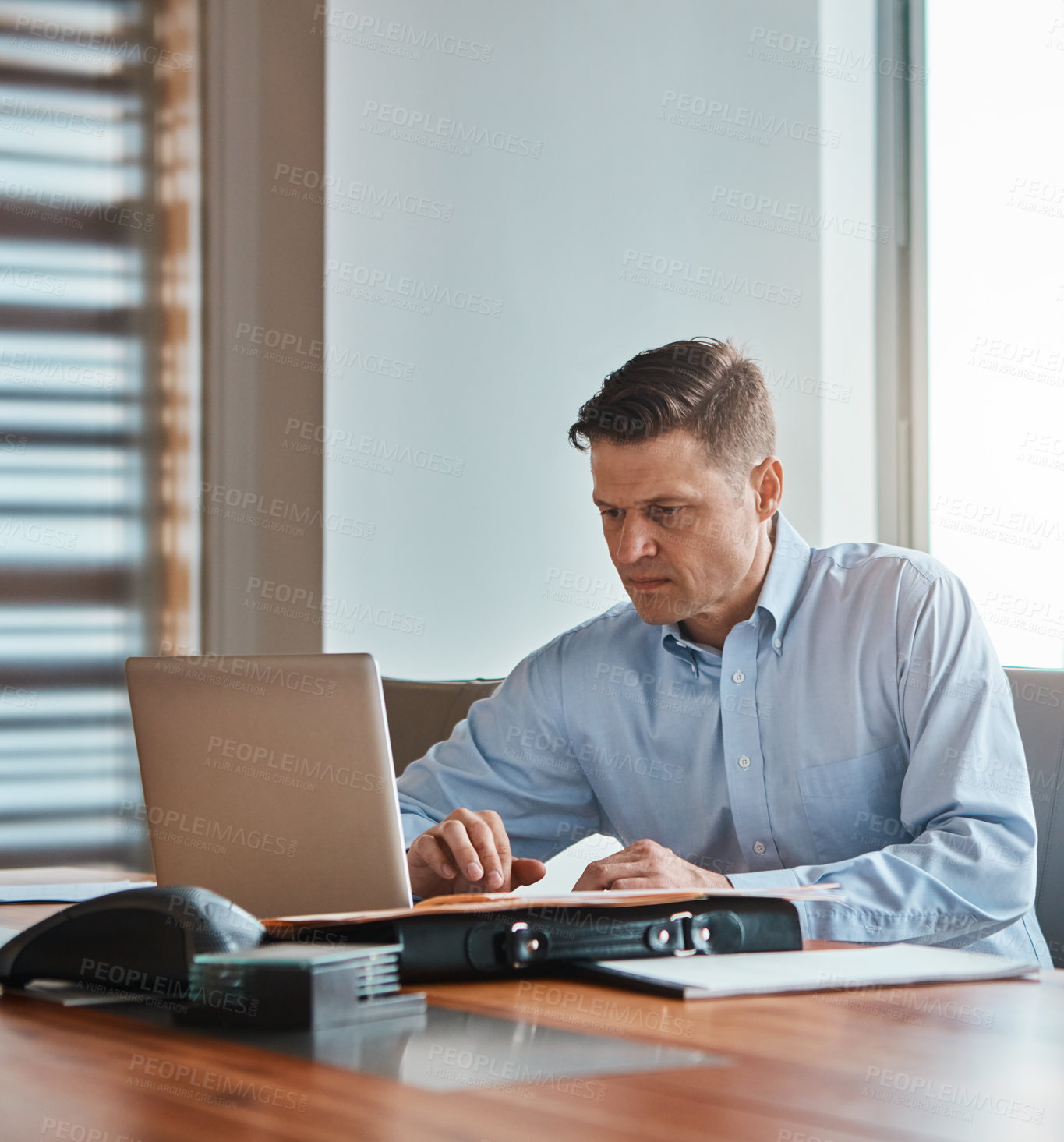 Buy stock photo Shot of a mature businessman working at his desk