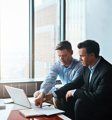 Buy stock photo Shot of two businessmen having a discussion while sitting by a laptop