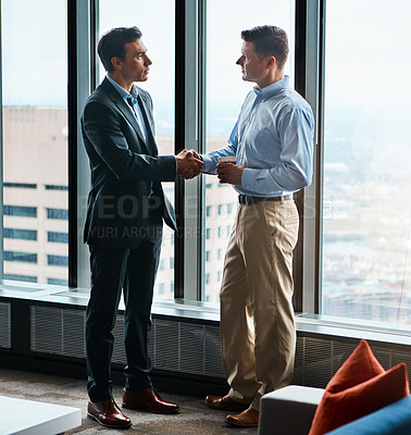 Buy stock photo Shot of two businessmen shaking hands in a corporate office