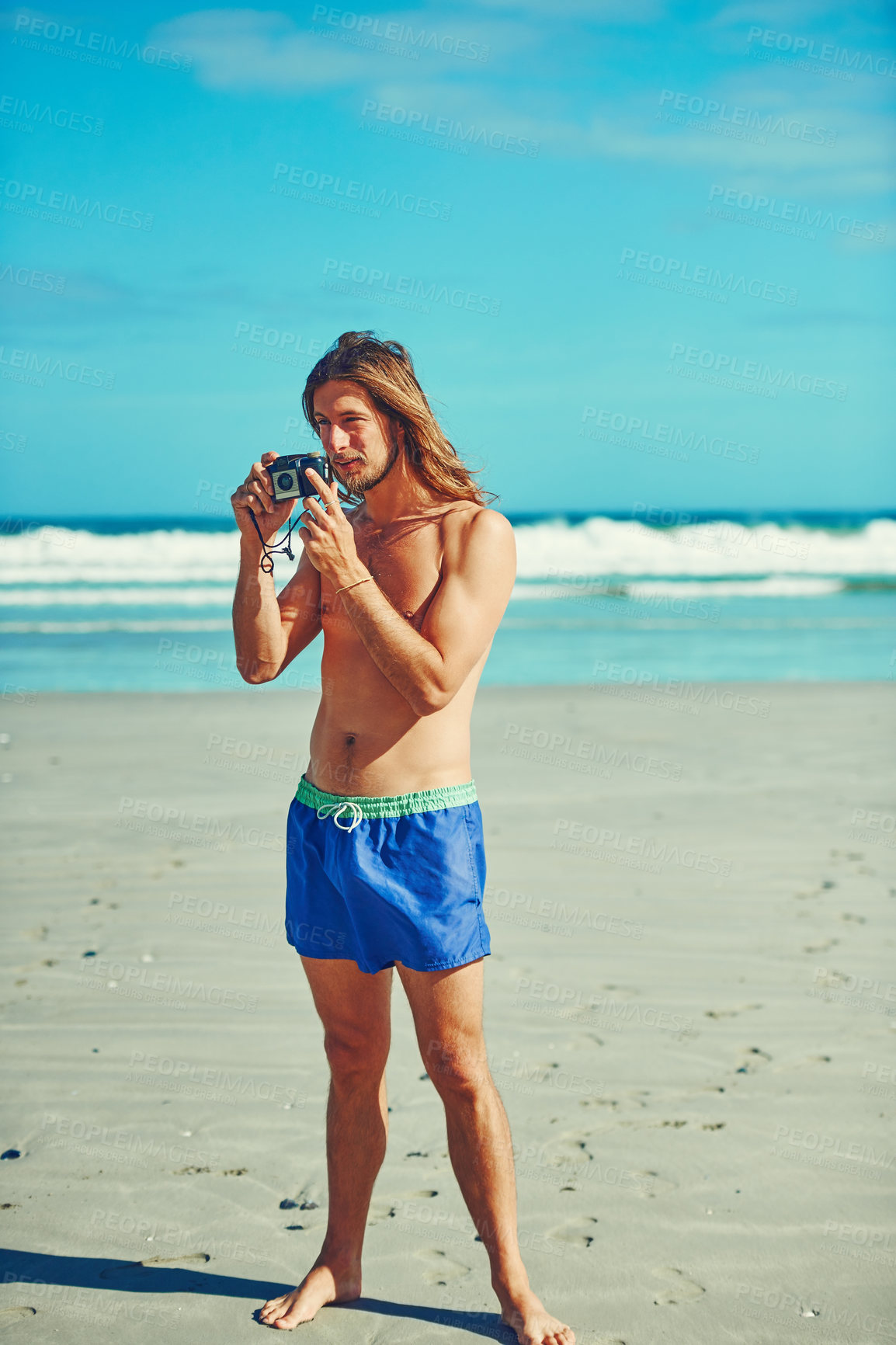 Buy stock photo Shot of a young man spending the day at the beach