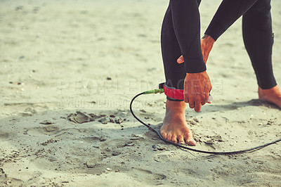 Buy stock photo Cropped shot of a surfer tying his surfboard leash around his ankle