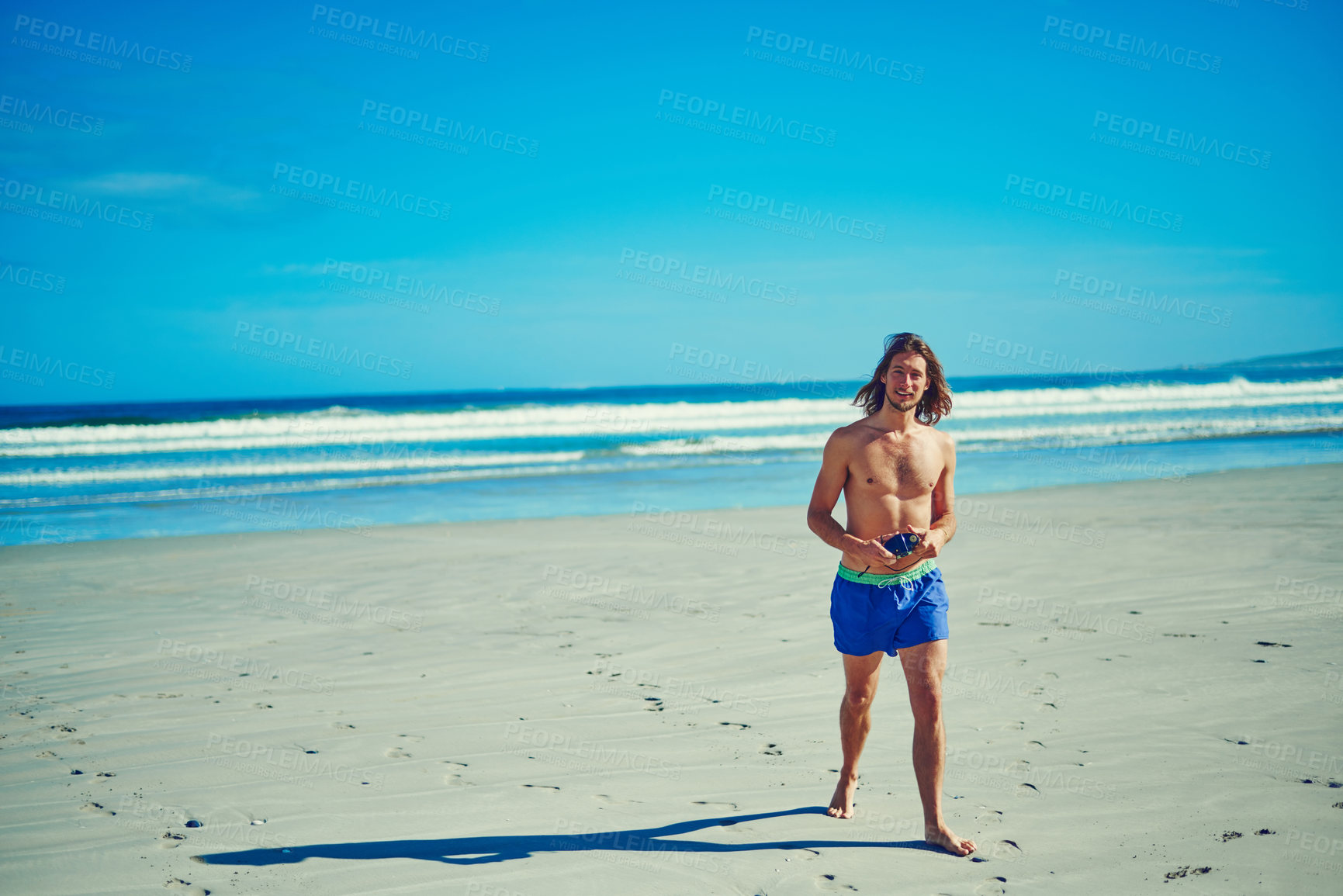 Buy stock photo Shot of a young man spending the day at the beach