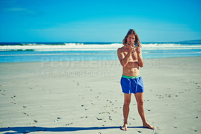 Buy stock photo Shot of a young man spending the day at the beach