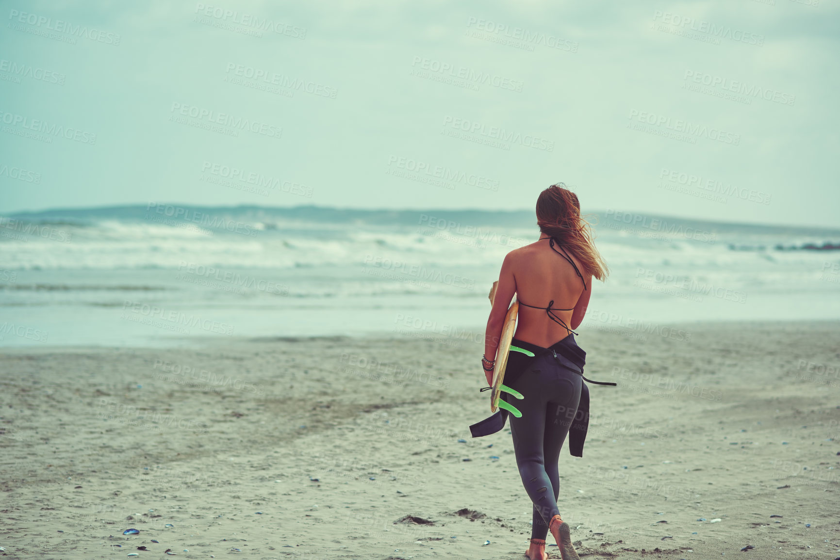 Buy stock photo Shot of a young surfer carrying her surfboard on the beach
