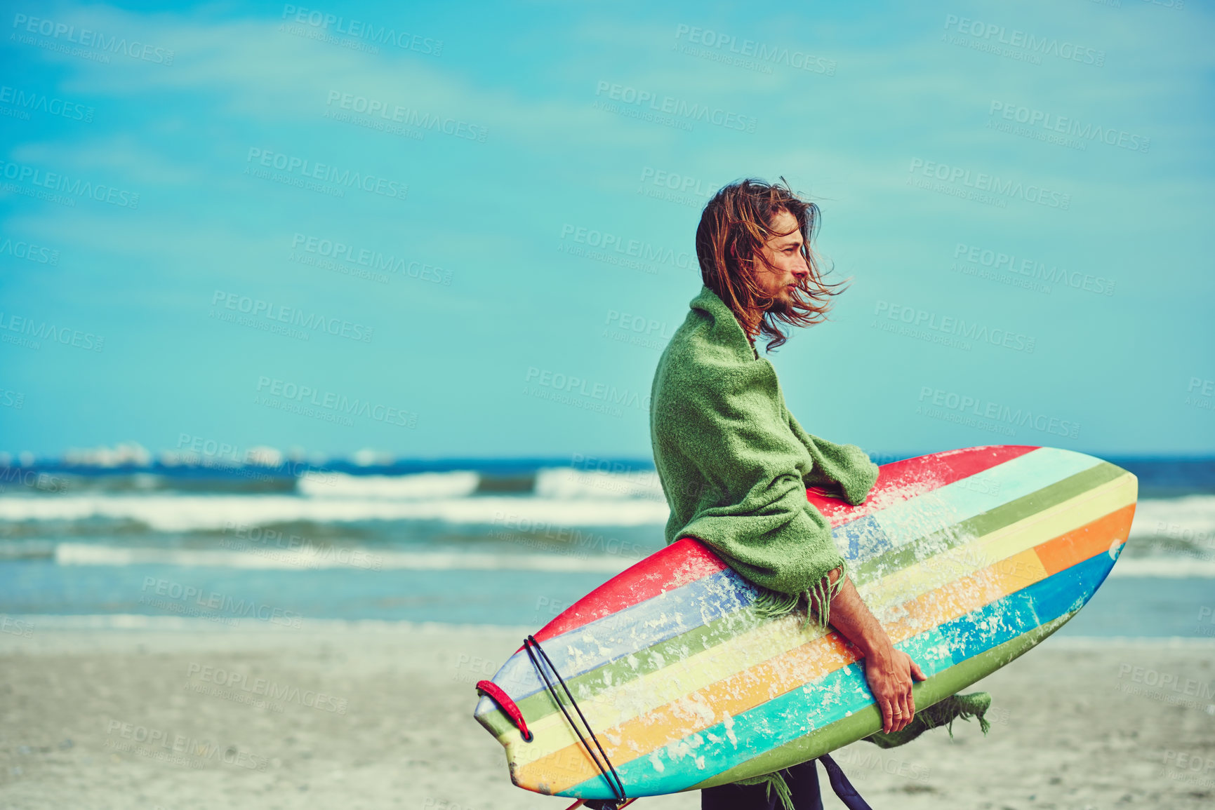 Buy stock photo Shot of a young surfer strolling on the beach with his surfboard