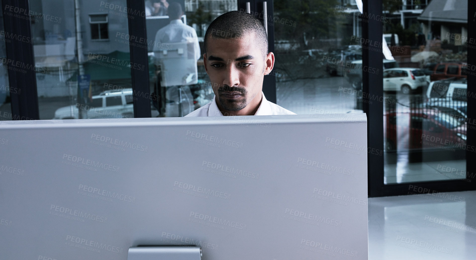 Buy stock photo Shot of a young businessman using a computer at night in a modern office