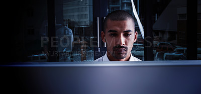 Buy stock photo Shot of a young businessman using a computer at night in a modern office