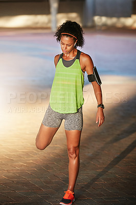Buy stock photo Shot of a sporty young woman warming up before a run outside