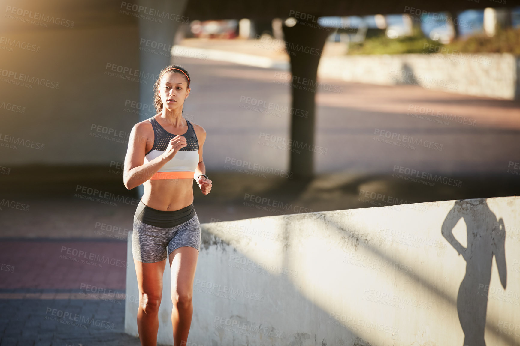 Buy stock photo Cropped shot of an attractive young woman taking a run through the city