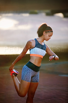 Buy stock photo Cropped shot of an attractive young woman stretching before a run through the city