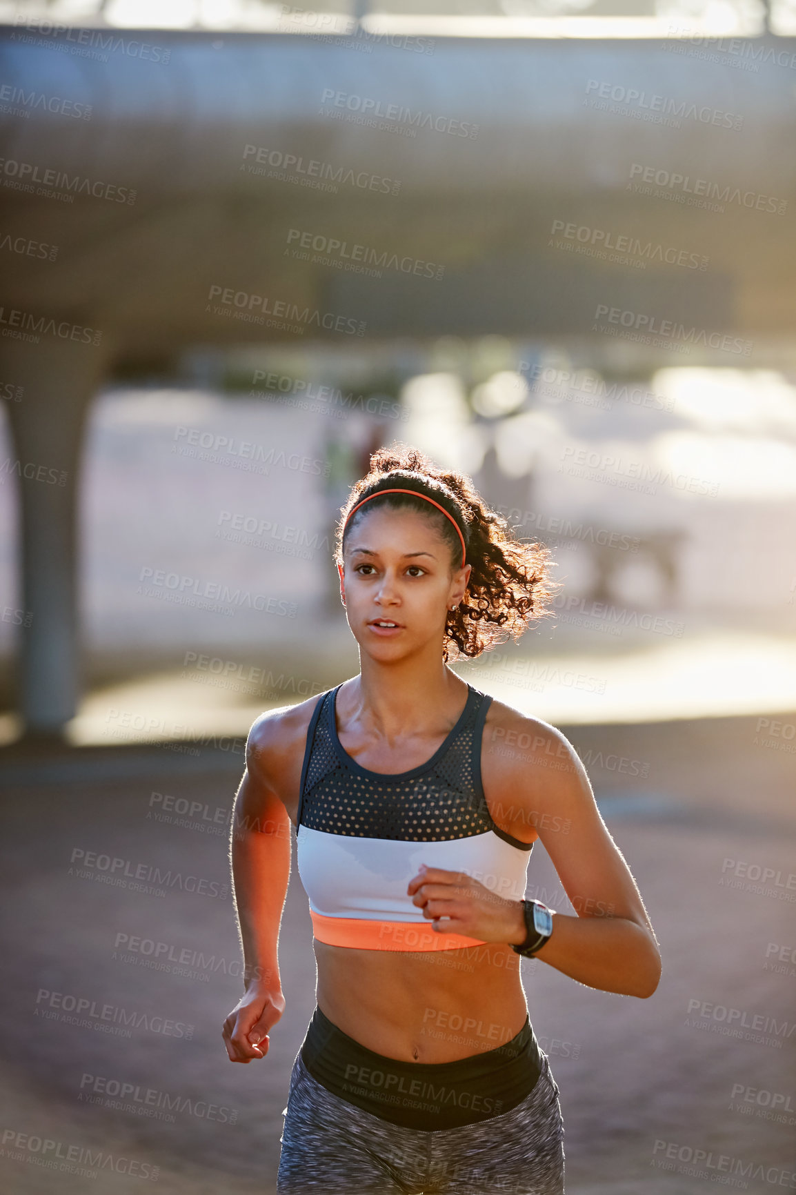 Buy stock photo Cropped shot of an attractive young woman taking a run through the city