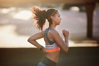 Buy stock photo Cropped shot of an attractive young woman taking a run through the city