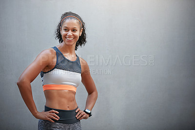 Buy stock photo Cropped shot of a sporty young woman standing with her hands on her hips in front of a grey wall