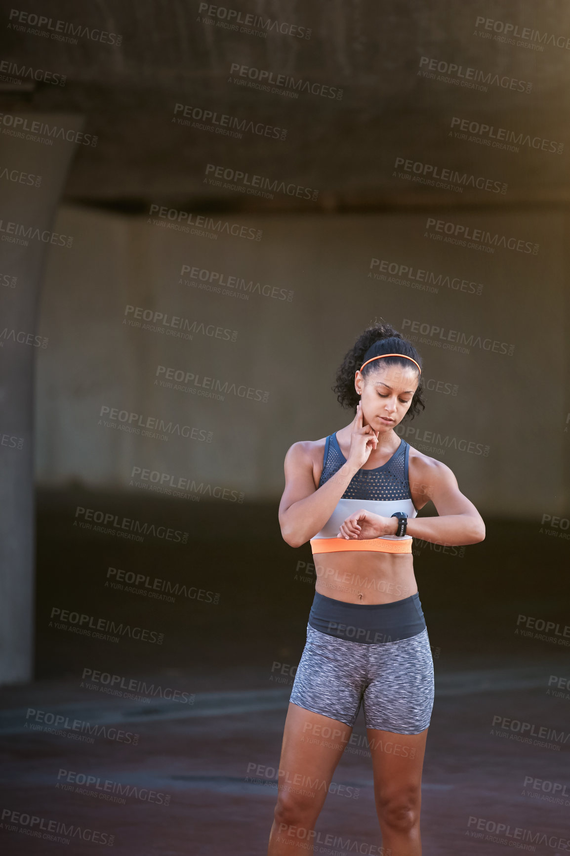 Buy stock photo Cropped shot of an attractive young woman checking her heart rate during a run through the city