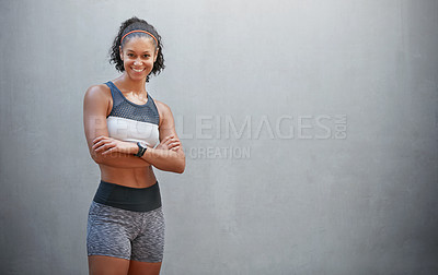 Buy stock photo Cropped portrait of a sporty young woman standing with her arms folded in front of a grey wall