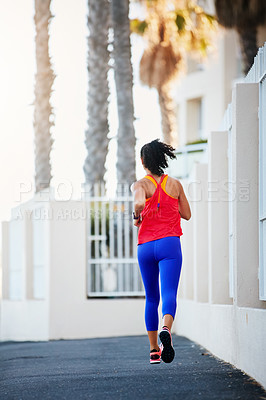 Buy stock photo Rearview shot of a sporty young woman out running in the city by herself