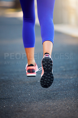 Buy stock photo Low angle shot of a sporty woman our running on a road