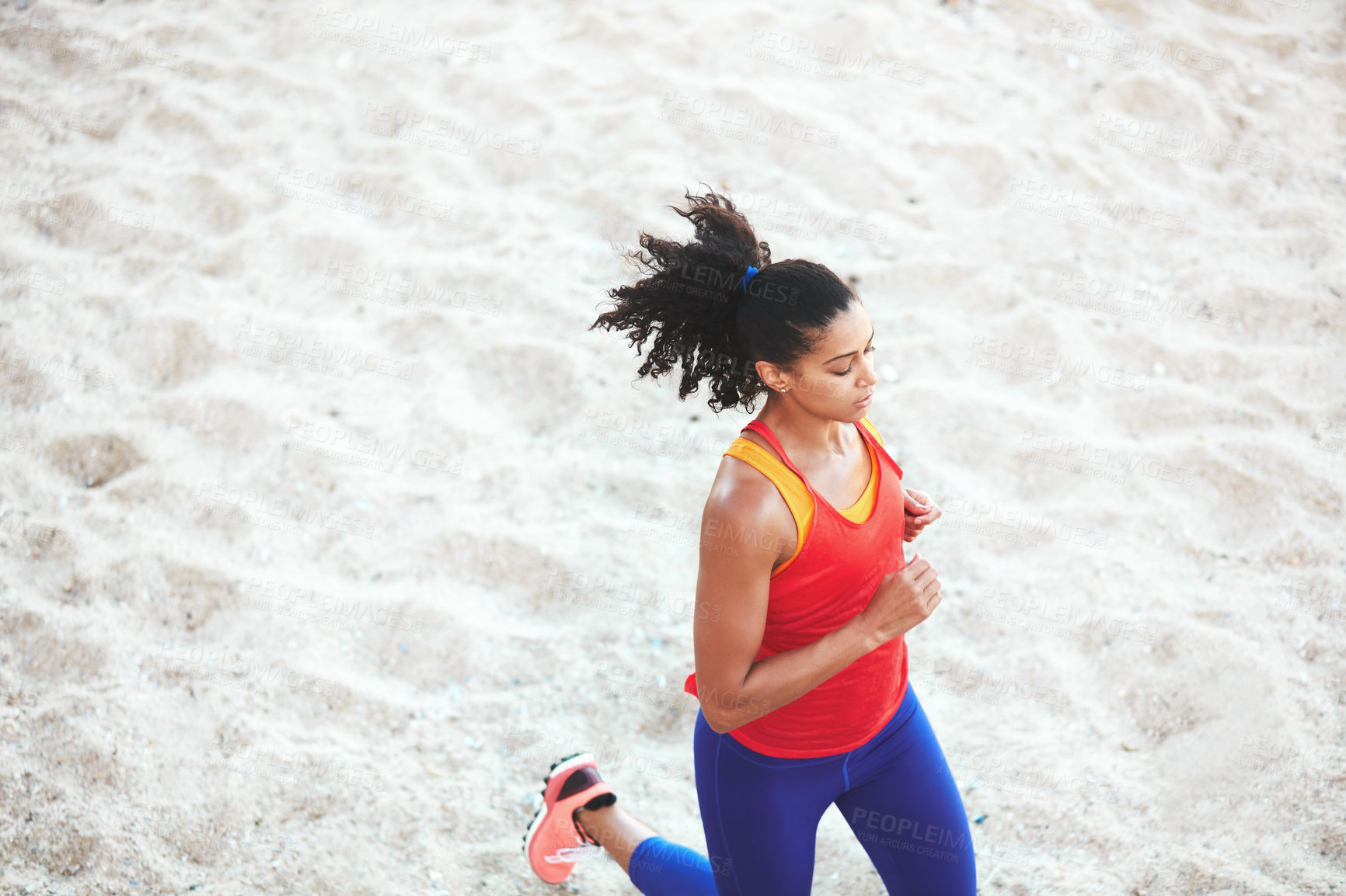 Buy stock photo Shot of a sporty young woman out at the beach for her morning run