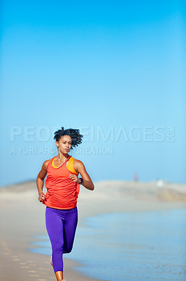 Buy stock photo Shot of a sporty young woman out at the beach for her morning run