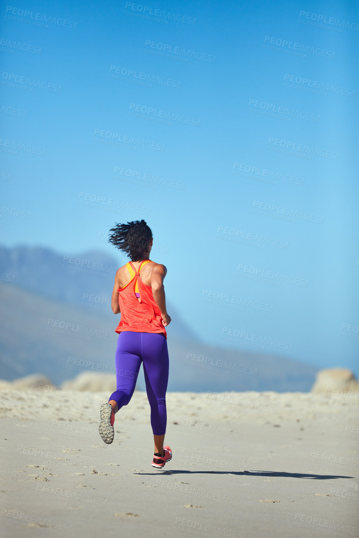 Buy stock photo Shot of a sporty young woman out at the beach for her morning run