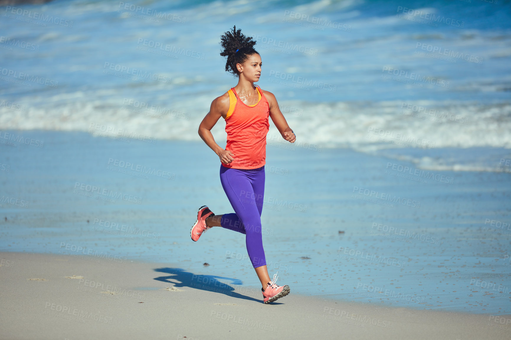 Buy stock photo Shot of a sporty young woman out at the beach for her morning run