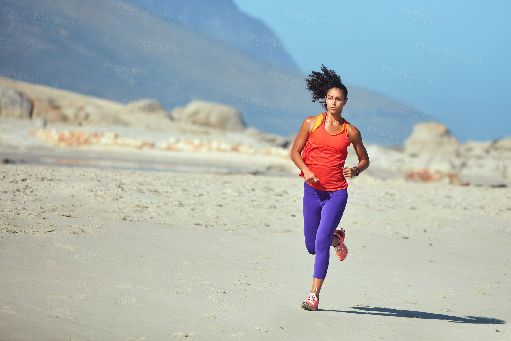 Buy stock photo Shot of a sporty young woman out at the beach for her morning run