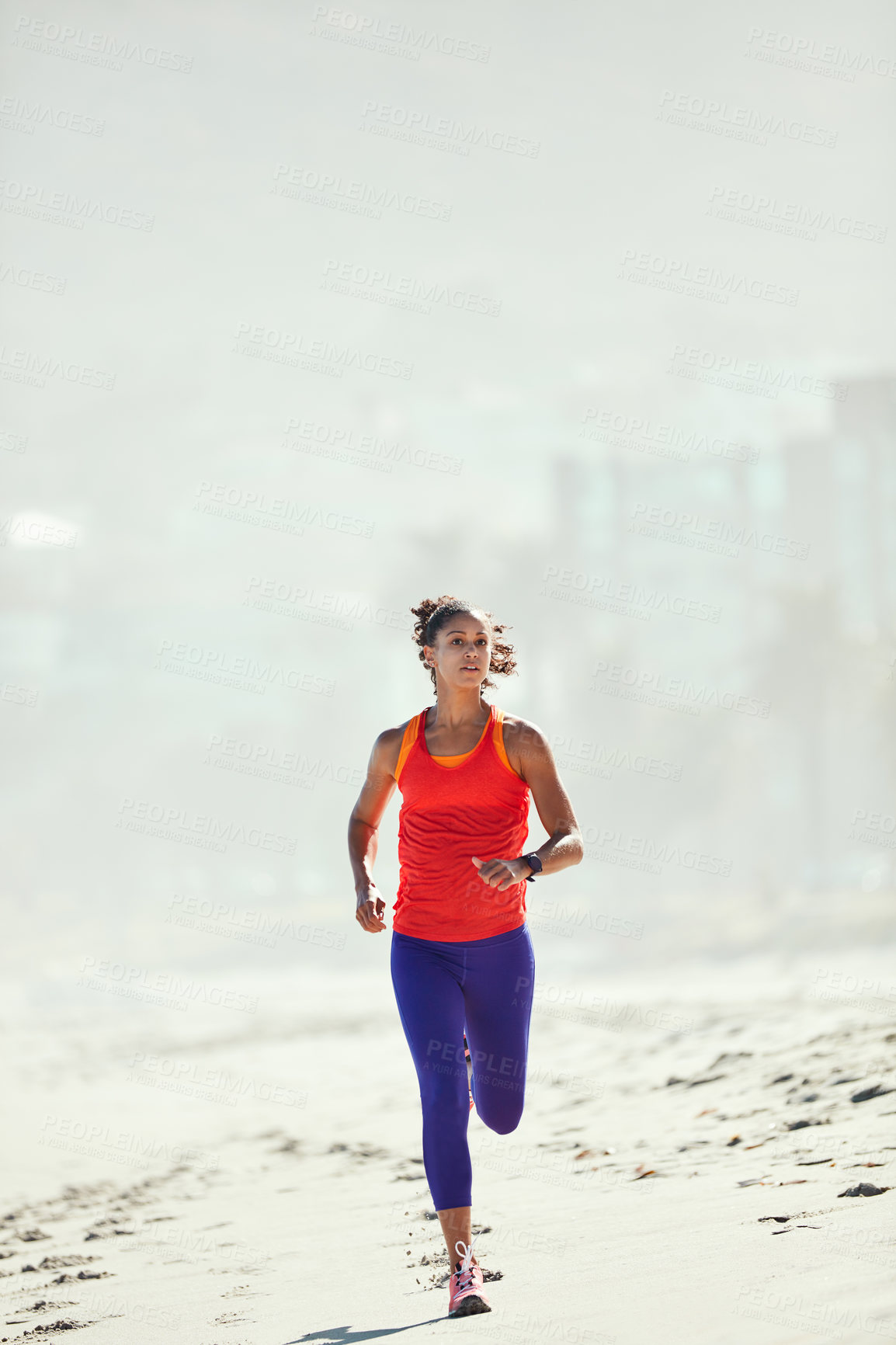 Buy stock photo Shot of a sporty young woman out at the beach for her morning run