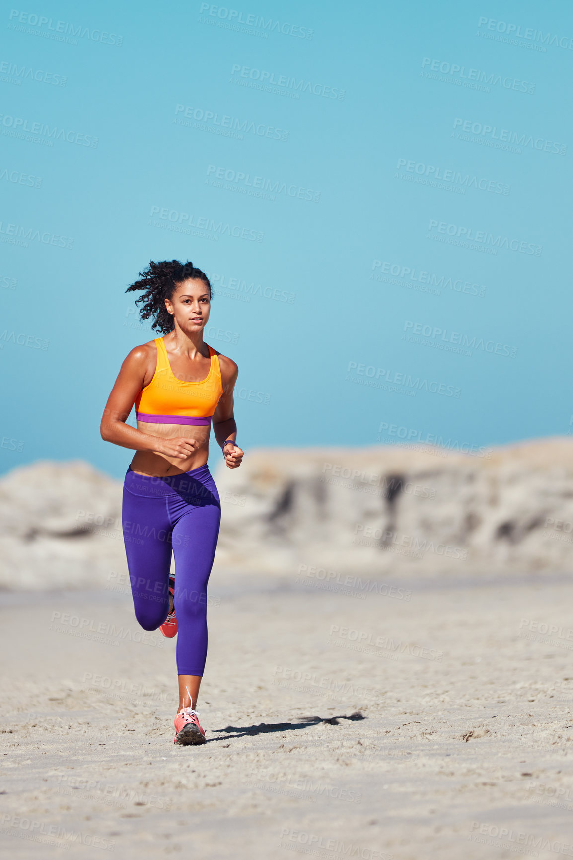 Buy stock photo Shot of a sporty young woman out at the beach for her morning run