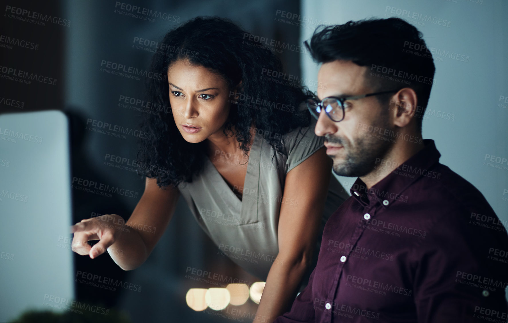 Buy stock photo Shot of two colleagues using a computer together during a late night at work