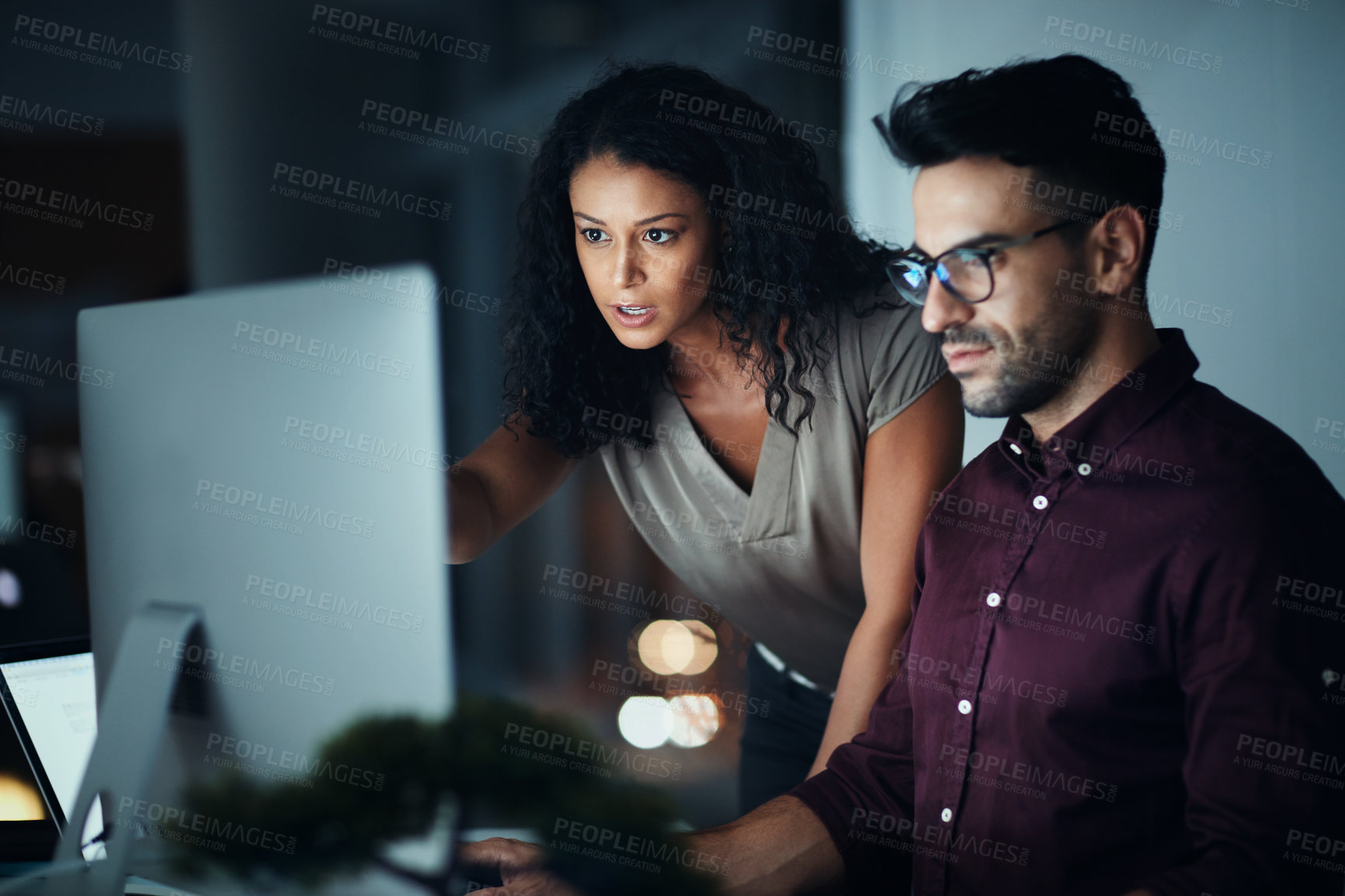 Buy stock photo Shot of two colleagues using a computer together during a late night at work